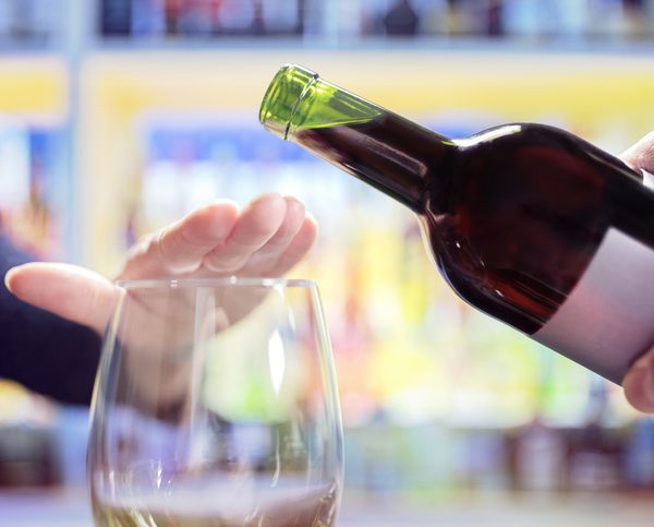 Woman rejecting more alcohol from wine bottle in bar