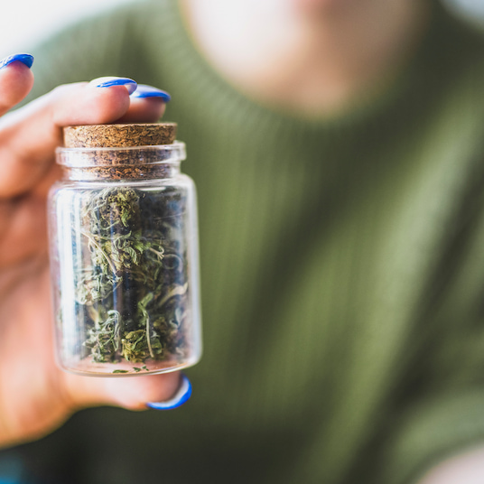 How Long Do Cannabis Withdrawals Last? - an image of a woman holding a small jar that contains marijuana