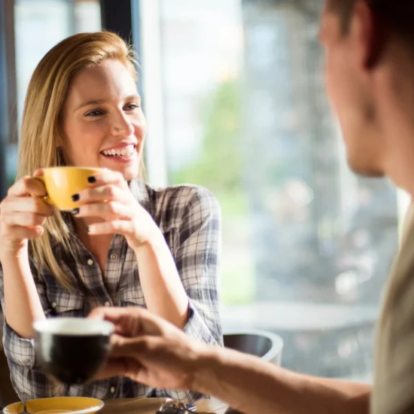 Benefits of Drinking Less Alcohol - an image of a smiling woman drinking coffee with a friend.